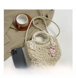 Détails du sac à main en paille tressée avec dentelle blanche et broderies de fleurs roses