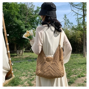 Detail view of a large woven knit shoulder bag with tassels and bohemian hollow pattern