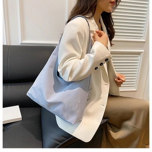 Détail du grand sac cabas bleu clair en PU avec texture plissée porté par un modèle