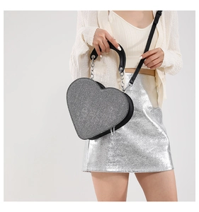 Sac cœur argenté pailleté en similicuir porté avec une jupe métallisée pour un look chic