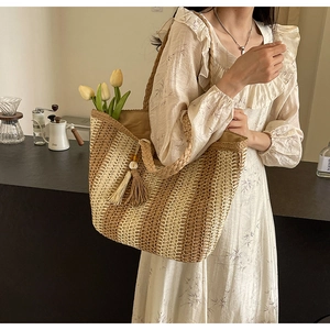 Detail of woven straw tote bag with khaki stripes, fringe tassel and sturdy handles