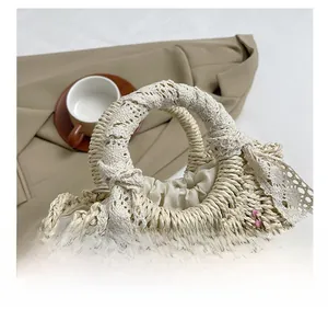 Détail du sac en paille tissée avec broderie florale et poignée ornée de dentelle
