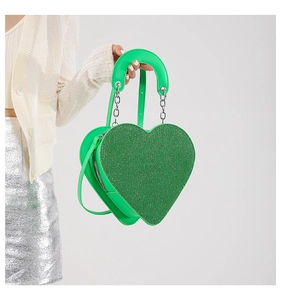 Détail du sac à bandoulière vert en forme de cœur avec paillettes et chaîne en métal