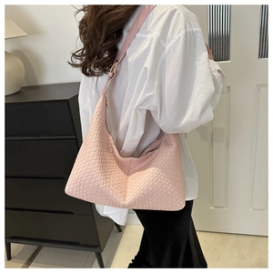 Pink woven PU leather hobo bag worn by model in a minimalist home interior setting