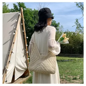 Detail of hand-woven cream knit texture and thick shoulder strap on a tote bag