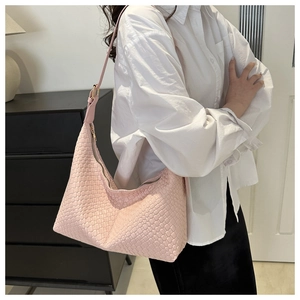 Detail of pink woven PU leather hobo bag worn by model on a white shirt