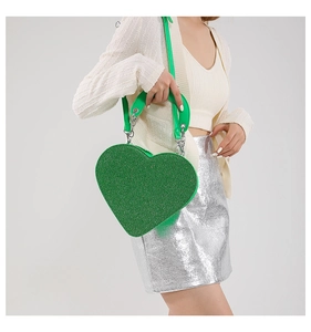 Détail du sac à main coeur vert pailleté avec bandoulière chaîne sur jupe argentée