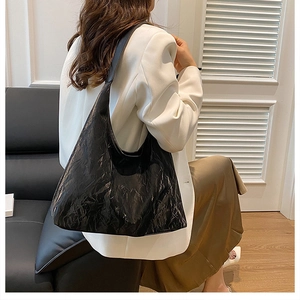 Détail de la texture en cuir PU noir brillant et plissé sur un sac fourre-tout chic