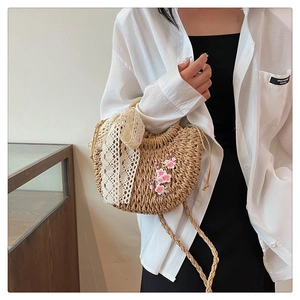 Détail du sac à main en paille tissée avec broderie cerisier et nœud en dentelle blanche