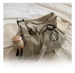 Detail of beige nylon drawstring bucket bag with adjustable strap and plush cup charm