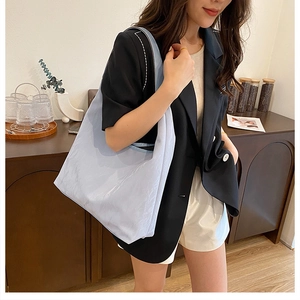 Détail du grand sac hobo bleu clair avec texture plissée brillante porté par un mannequin