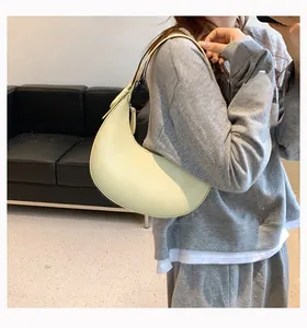 Detail of a minimalist pale yellow half-moon PU leather shoulder bag for daily casual use