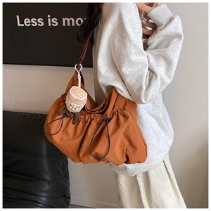 Detail of trendy burnt orange fabric crossbody bag with drawstring ruching and plush charm