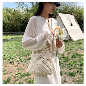 Bohemian off-white woven hollow handbag styled with a long dress in a garden setting