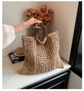 Detail of woven straw tote bag with brown leather handles and reinforced stitching
