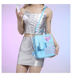 Detail of light blue Y2K rotary phone crossbody bag with heart pattern and retro receiver