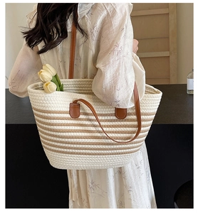 Close-up of handmade woven tote bag with brown leather straps shown on model
