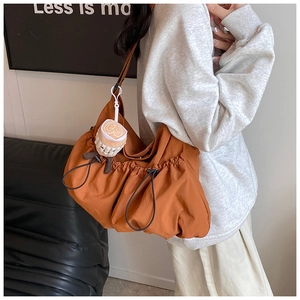 Detailed side view of orange pleated nylon tote bag with a plush coffee cup charm