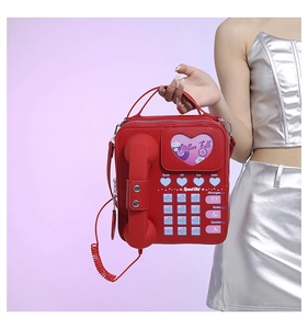 Macro detail of red vintage telephone shaped handbag featuring functional dial and phone handle