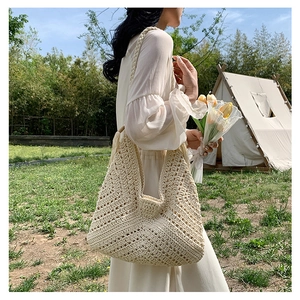 Close-up of beige crochet knit hobo bag with geometric hollow patterns and woven strap