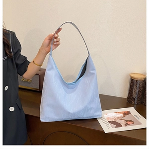 Détail du sac hobo bleu clair avec une texture plissée unique sur une table en bois