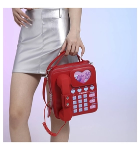 Creative red vintage telephone shaped crossbody bag with heart detail shown on model
