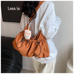 Detail of caramel nylon cloud bag featuring drawstring design and plush coffee cup charm