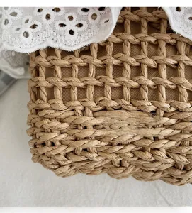 Detail of woven straw handbag featuring rustic mesh texture and delicate white lace trim