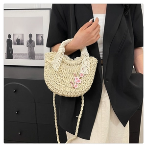Détail du sac croissant tissé avec broderie florale rose et bordure de poignée en dentelle