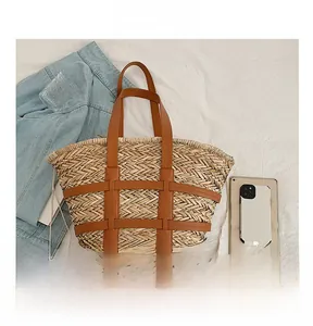 Detail view of woven straw tote bag with brown leather straps and cage reinforcement