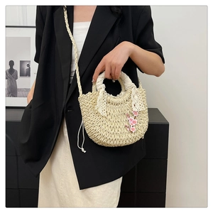 Détail du sac en paille tissée avec broderie cerisier et poignée ornée de dentelle