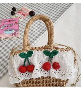 Detail of hand-woven straw bag featuring white lace trim and handmade crochet cherries