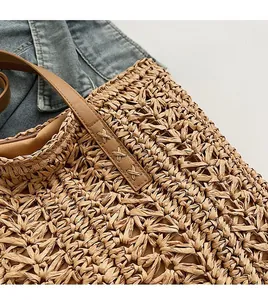 Detail of hand-woven straw tote bag with premium leather straps and durable X-shaped stitching