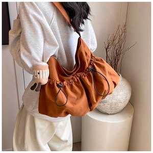 Detail of ginger nylon tote bag showing side drawstring design and plush cup charm