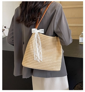 Détail du sac à main en paille avec nœud en dentelle blanche et poignée en cuir marron
