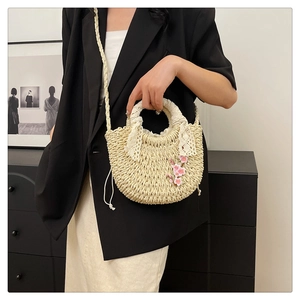 Détail du sac en paille tissée avec broderies florales, dentelle et cordon de serrage
