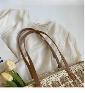 Détail du sac cabas en paille damier beige avec anses solides en cuir marron