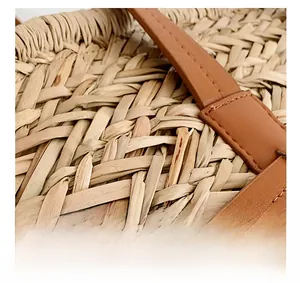 Detail of hand-woven straw texture and brown leather strap with precise stitching