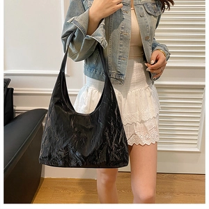 Sac hobo noir brillant plissé en cuir PU porté par un mannequin avec bandoulière élégante