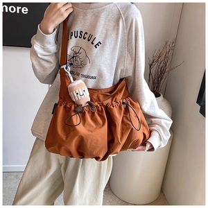 Close-up of caramel crossbody bag with pleated texture and coffee cup plush pendant