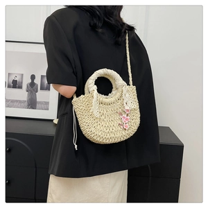 Détail du sac en paille tressée avec broderie de fleurs roses et poignée en dentelle