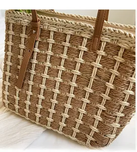 Détail du motif en damier de paille tressée et de la poignée en cuir marron du sac cabas