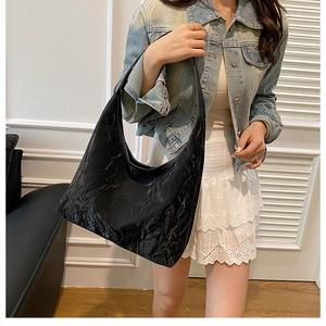 Détail de la texture froissée noire et de la surface en cuir PU brillant du grand sac hobo