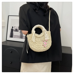 Détail du sac à main en paille tissée avec nœud en dentelle et broderie de fleurs