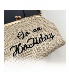 Détail du sac en paille avec broderie Go on Holiday et chaîne à billes dorée