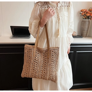Close-up of woven straw tote bag with brown leather handles in a chic home setting