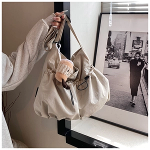 Detail view of khaki nylon crossbody bag with side drawstring and plush coffee cup charm