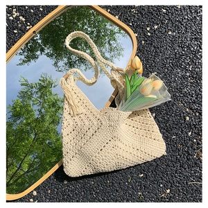 Bohemian off-white crochet shoulder bag with fringes and woven strap on stone background