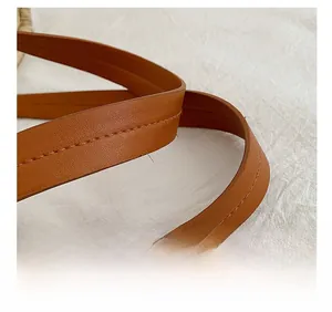 Detailed macro view of high-quality brown leather strap with durable stitching on woven bag