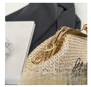 Gros plan sur un sac en paille beige avec ferrures dorées et broderie noire élégante